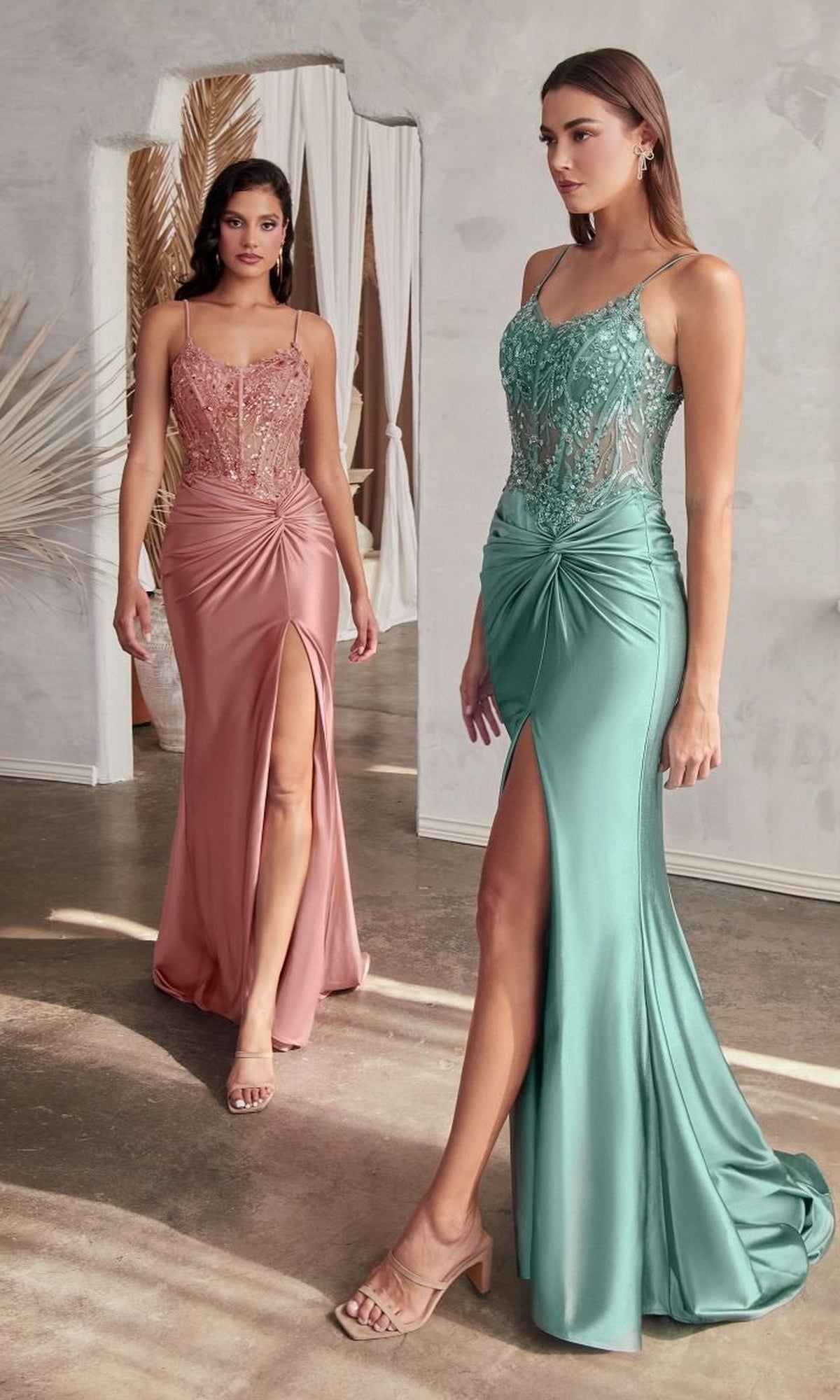 Two women, one wearing a pink dress and the other wearing a blue dress, standing indoors.